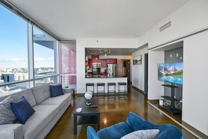 A modern apartment with a living room, kitchen, and dining area, large windows, and a city view.