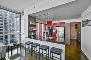 A modern kitchen with a central island, stainless steel appliances, and a view of a cityscape through large windows.