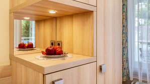 A wooden cabinet with a mirror, a plate of apples, and a window with curtains.