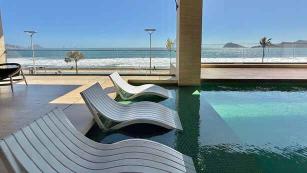 Area piscina con lettini e vista sulla spiaggia e sull'oceano.