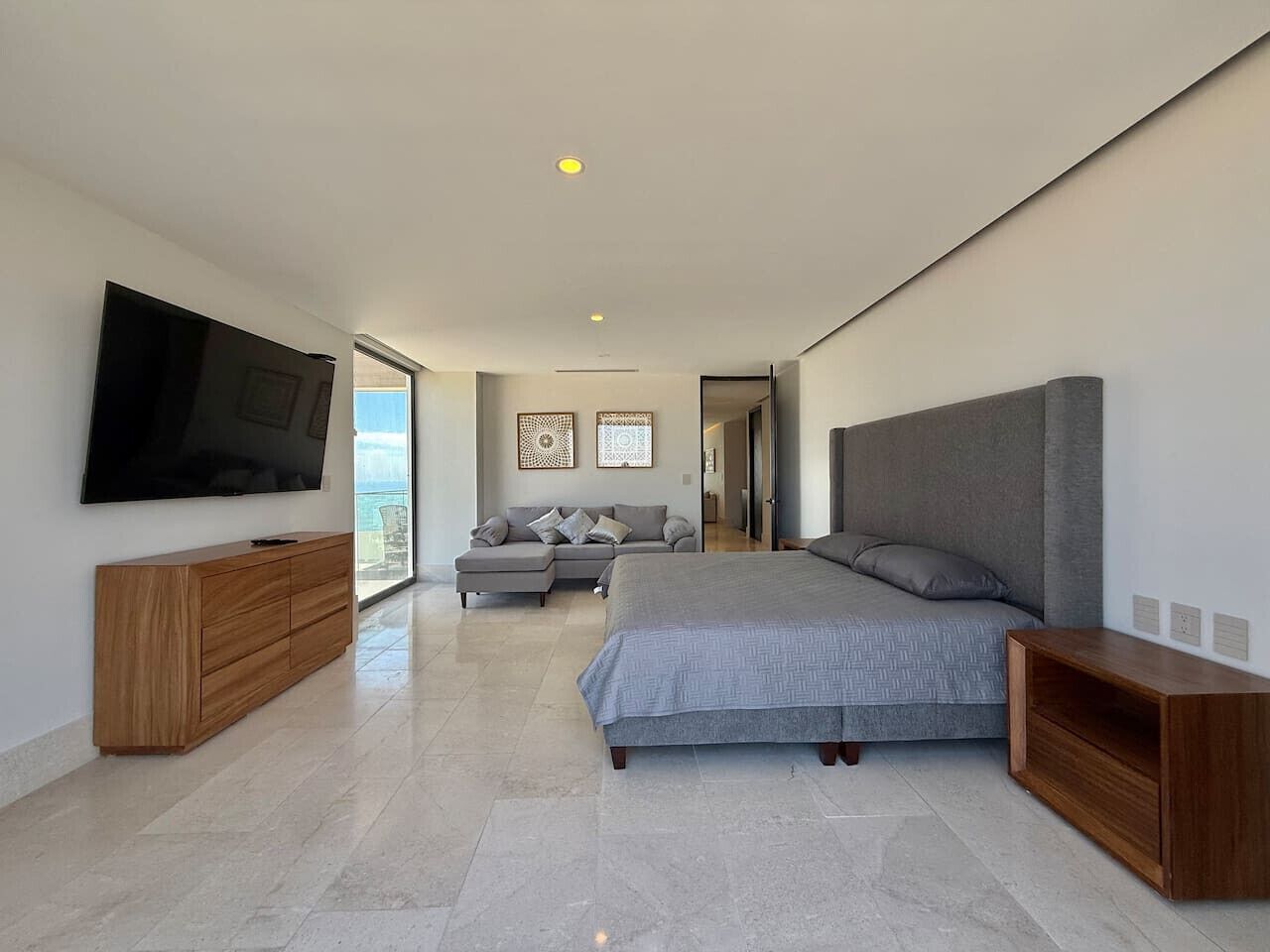 Une chambre moderne avec un grand lit, une télévision, un canapé et une armoire en bois.