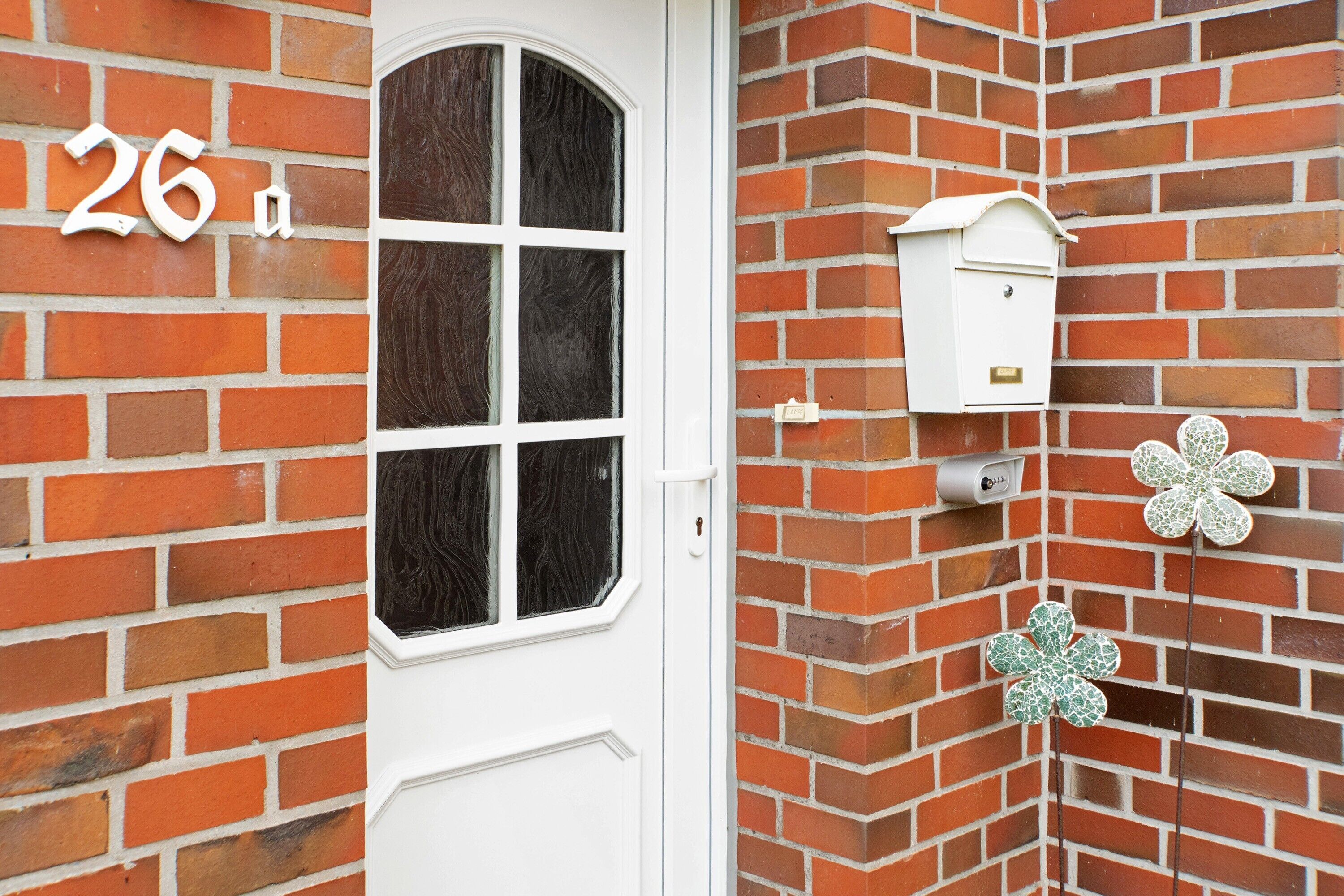 A brick wall with a white door, a mailbox, and a flower-shaped decoration.