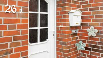 A brick wall with a white door, a mailbox, and a flower-shaped decoration.