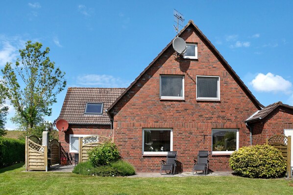 Een bakstenen huis met schuin dak, schotelantenne en twee ramen.