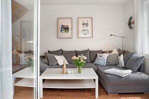 Ein modernes Wohnzimmer mit einem grauen Sofa, einem weißen Couchtisch und gerahmten Kunstwerken an der Wand.