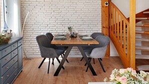 Comedor con pared de ladrillo, escalera de madera y una mesa dispuesta para cuatro.