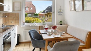 Una cocina compacta con zona de comedor, una ventana con vistas a casas y un pequeño cubo de basura.