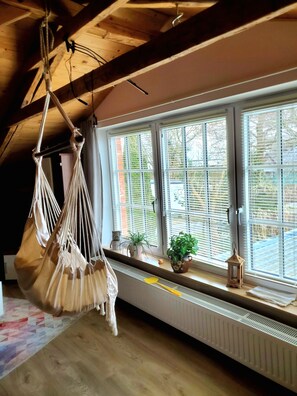 A room with a hammock, potted plants, and a radiator near large windows. - Guesthouse "Old Country House" with Shared Garden and Wi-Fi (Behrendorf)