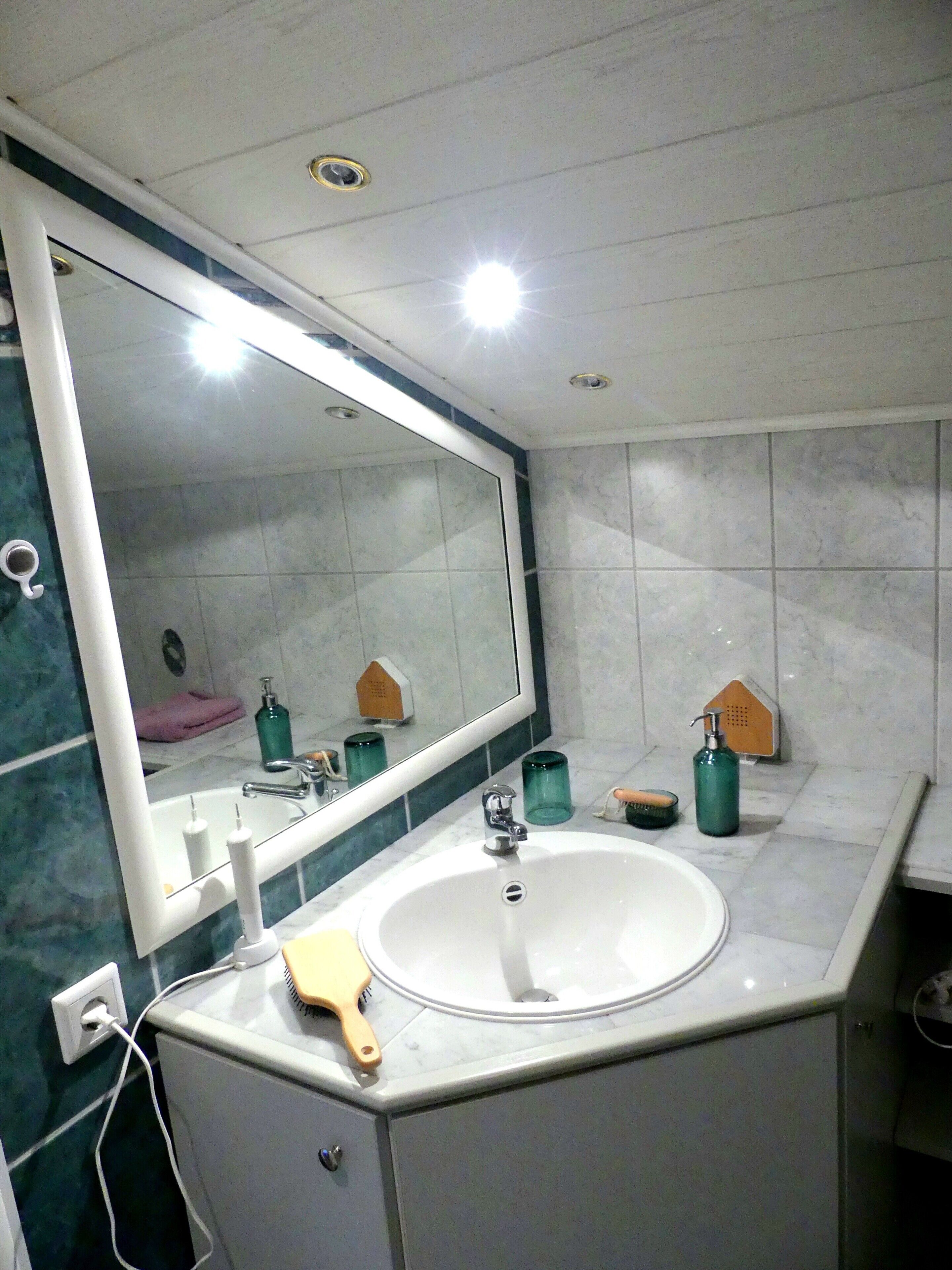 A bathroom with a large mirror, white sink, and tiled walls.
