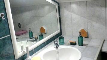 A bathroom with a large mirror, white sink, and tiled walls.