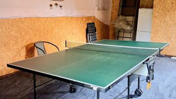 Une table de ping-pong dans une pièce aux murs en bois et dotée d’un ventilateur de plafond.