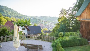 A patio area with a bench, an umbrella, and a wooden fence. - Baßler Schlossblick Apartment with Private Terrace, Balcony and Wi-Fi (Kappelrodeck)