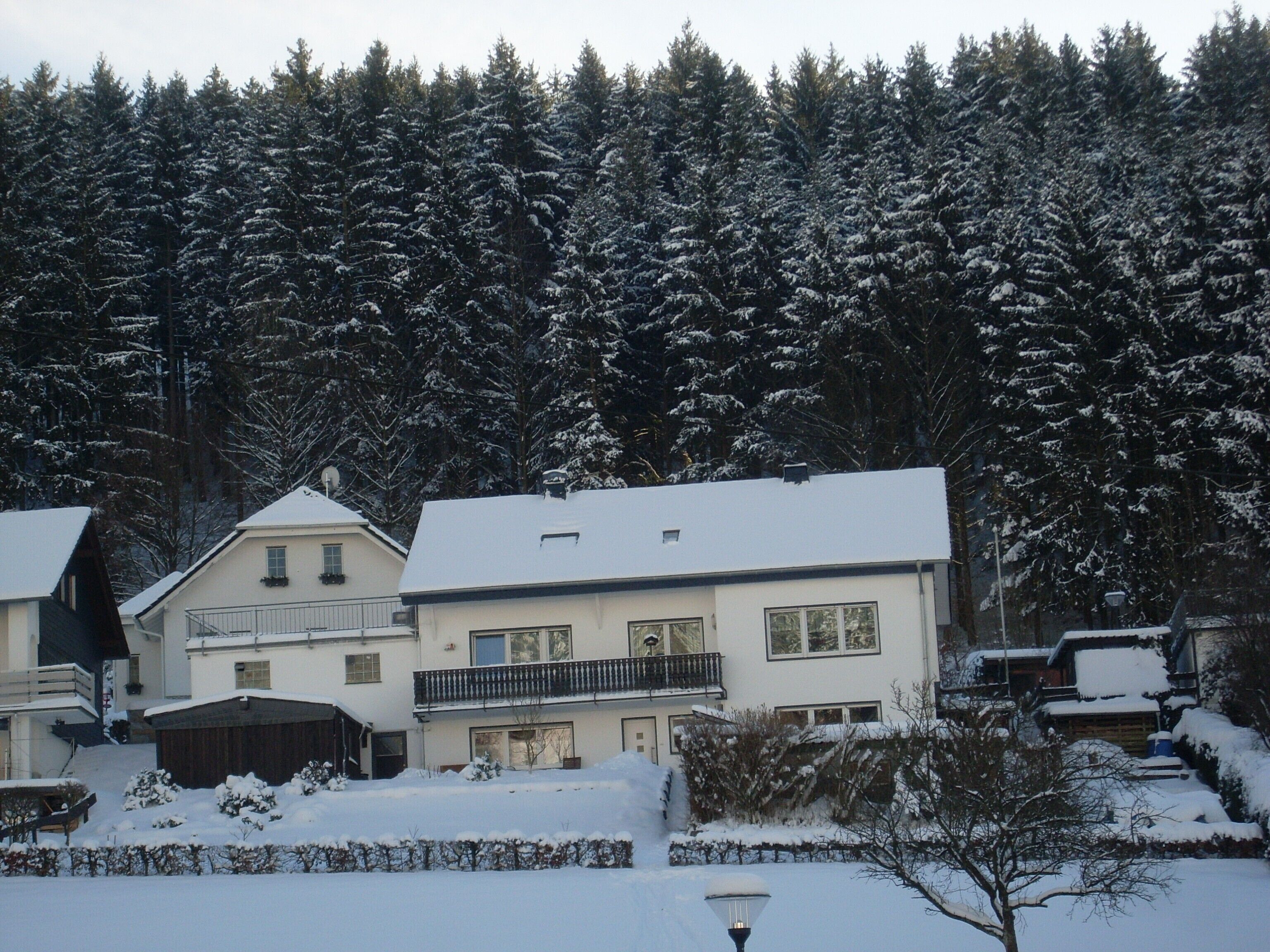 A residential building with a balcony, surrounded by snow-covered trees.