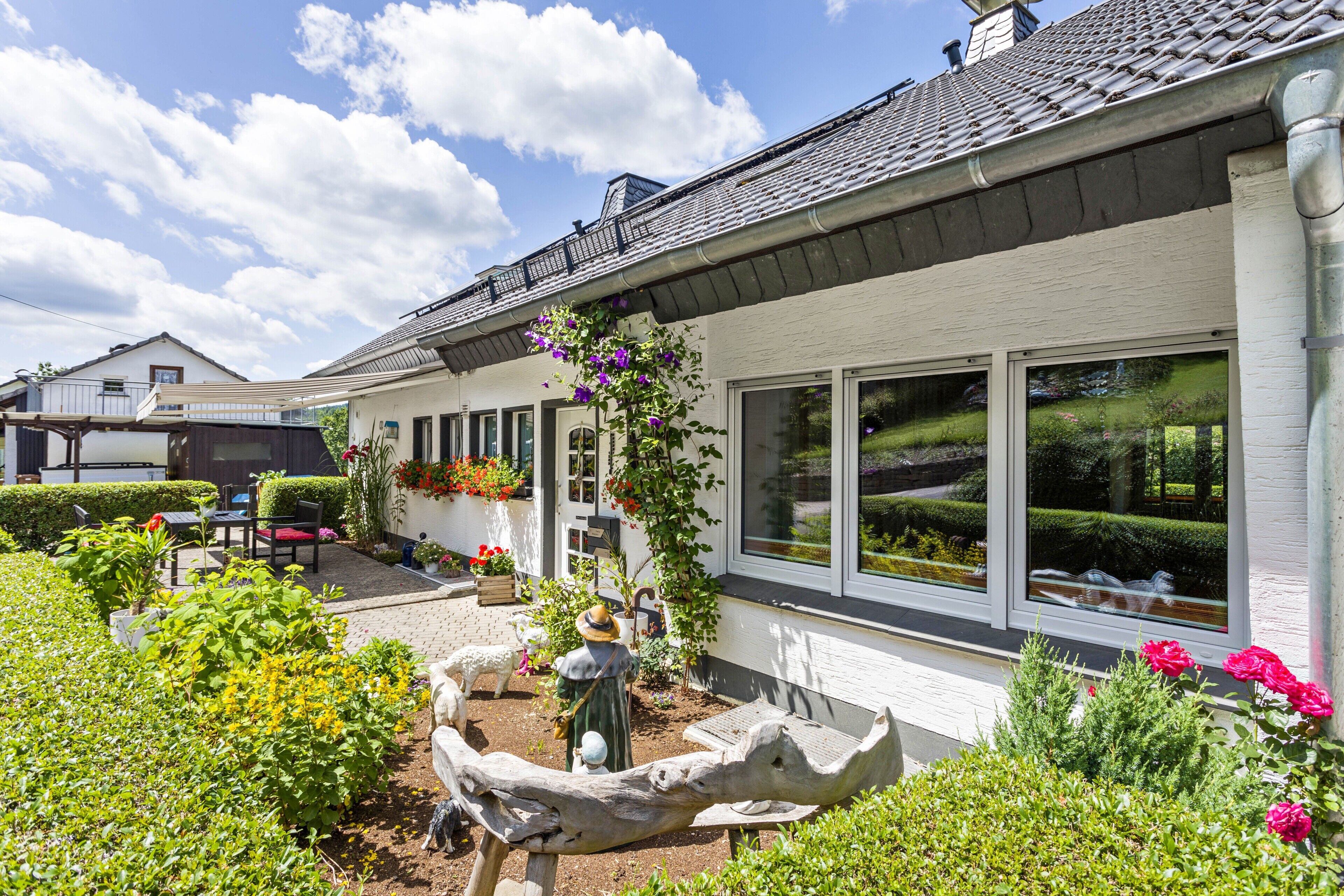 Ein Haus mit Garten, Terrasse und einem großen Fenster.