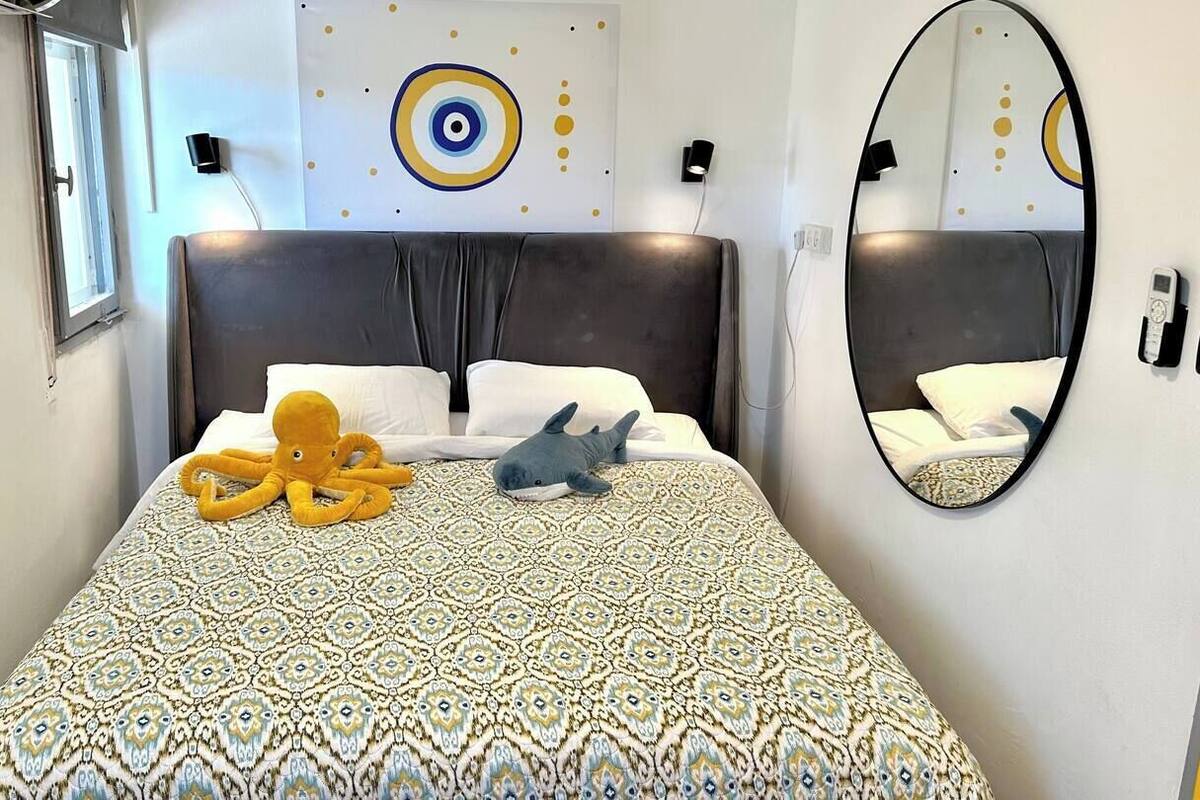 A bedroom with a patterned bedspread, a large mirror, and a wall with circular designs.