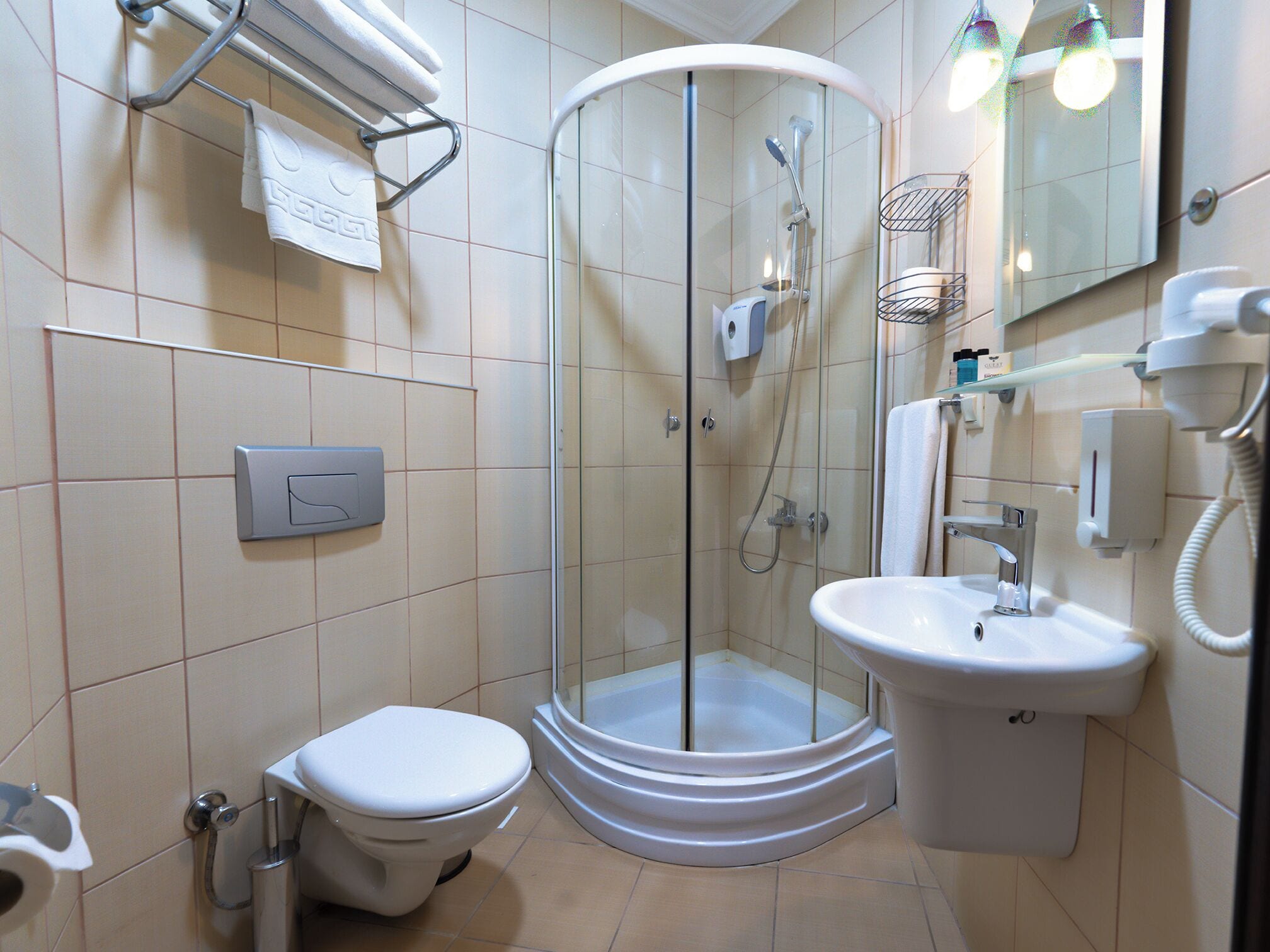 Ein modernes Badezimmer mit einer Duschkabine aus Glas, einer weißen Toilette, einem Waschbecken und einem Spiegel.