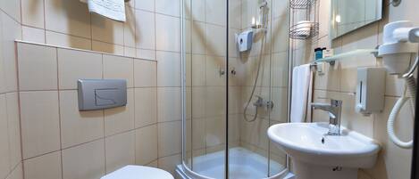 Un baño moderno con cabina de ducha de vidrio, un inodoro blanco, un lavamanos y un espejo.