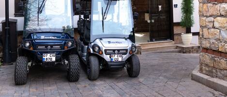 Two golf carts parked in front of a building with stone walls and a large wooden door.