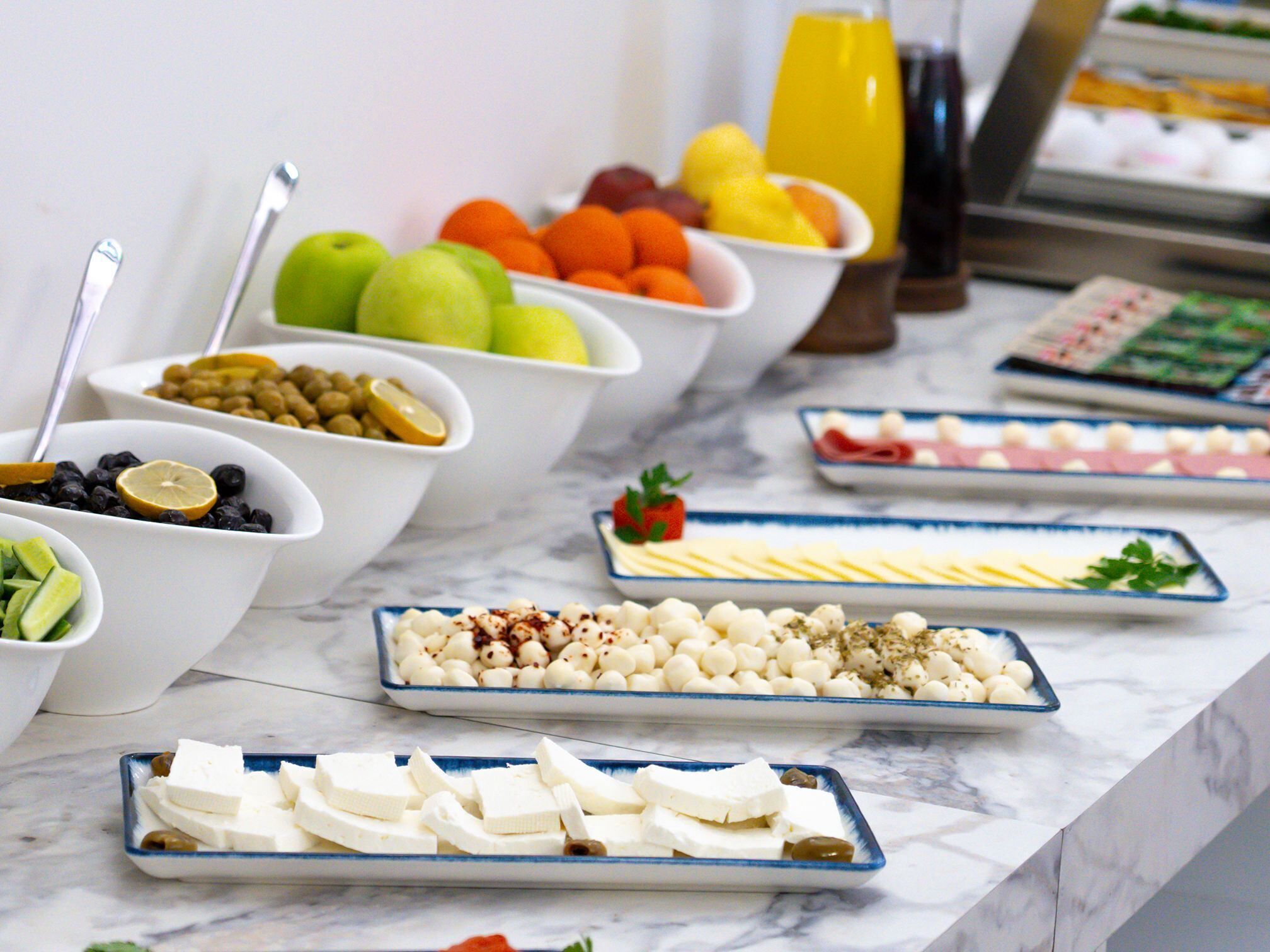 A buffet with various food items including fruits, cheeses, and olives.