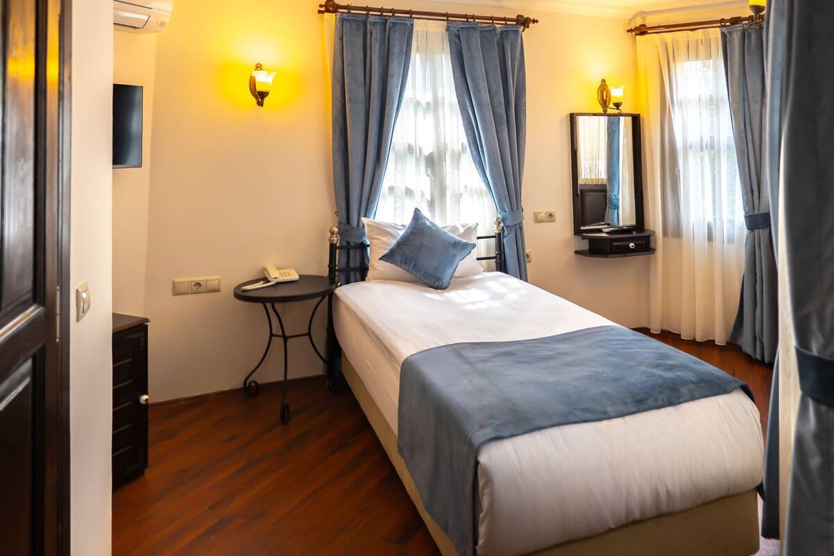 Ein Hotelzimmer mit Bett, Nachttisch, Lampe und Spiegel.