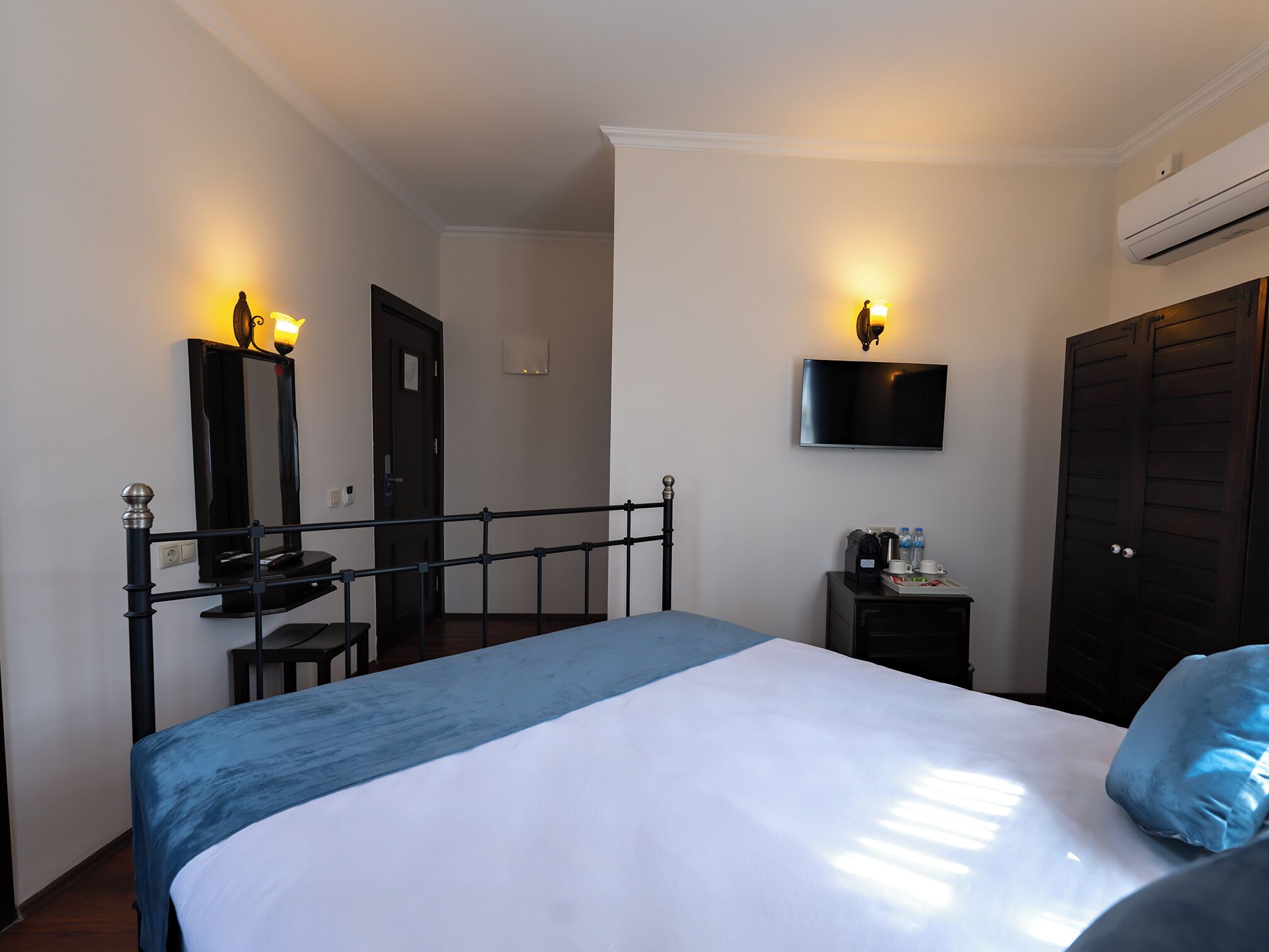 A hotel room with a bed, bedside table, TV, and wardrobe.