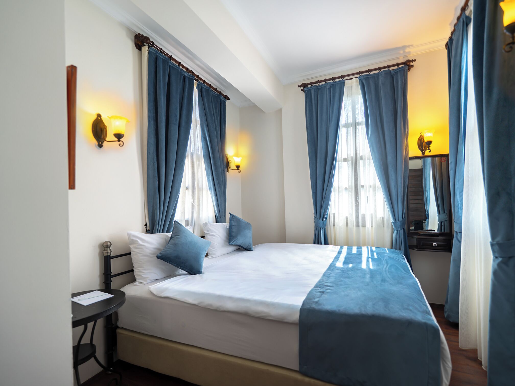 A bedroom with a bed, two bedside tables, and curtains.