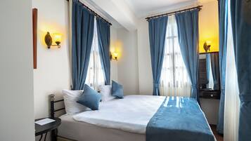 A bedroom with a bed, two bedside tables, and curtains.