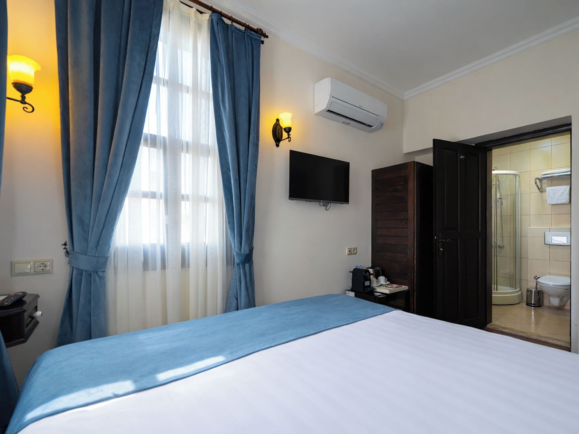 Une chambre d’hôtel équipée d’un lit, d’une télévision, d’un climatiseur, d’une douche et d’une salle de bain.