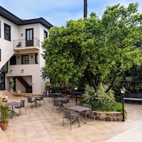 Un patio con mobiliario exterior, una escalera y un edificio con balcón.