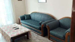 A living room with a sofa and a table, a door, and a window with curtains. - Sofia's house in Thiva (Thiva)