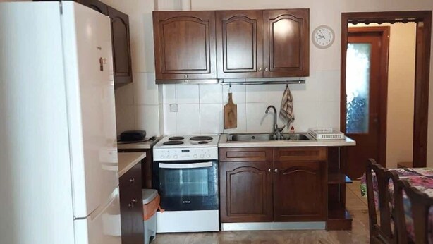 A compact kitchen with wooden cabinets, a stove, an oven, and a sink. - Sofia's house in Thiva (Thiva)