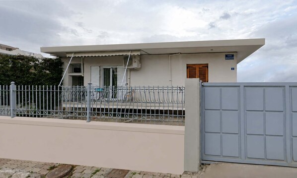 Un edificio moderno con techo plano, entrada portonada y un pequeño porche con un aparcamiento para bicicletas.