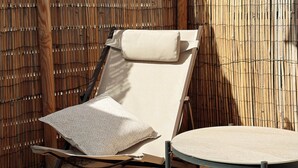 A sun lounger with a cushion and a small round table, positioned against a bamboo fence. - L'Atlantide Maison & Spa - Direct access to the beach (Saint-Hilaire-de-Riez)
