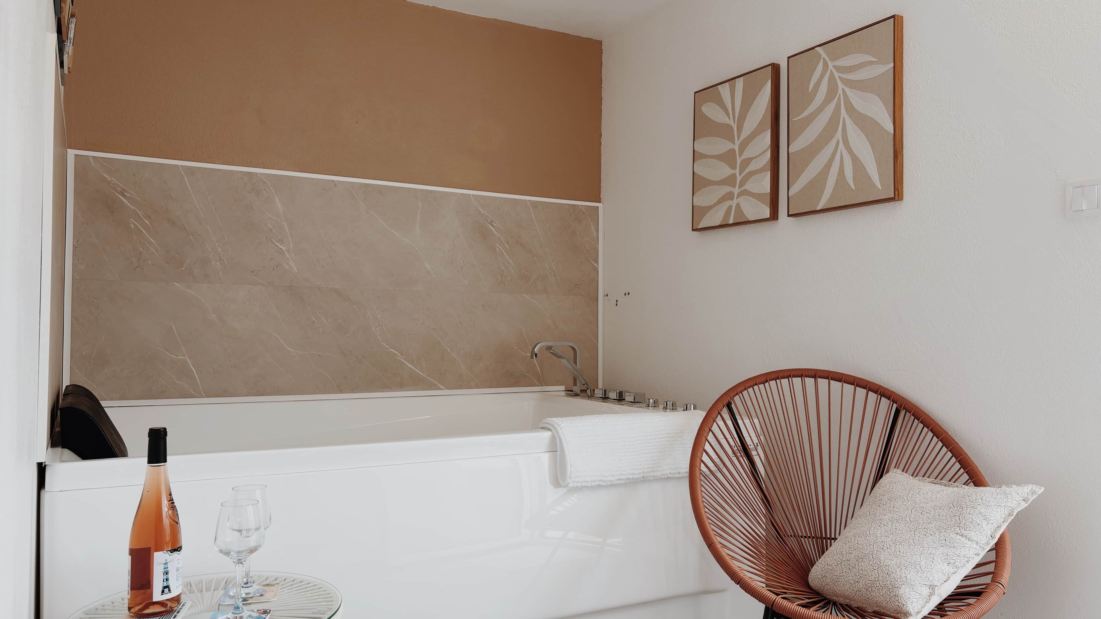Ein Badezimmer mit einer Badewanne, einem Korbstuhl und einem Handtuch.