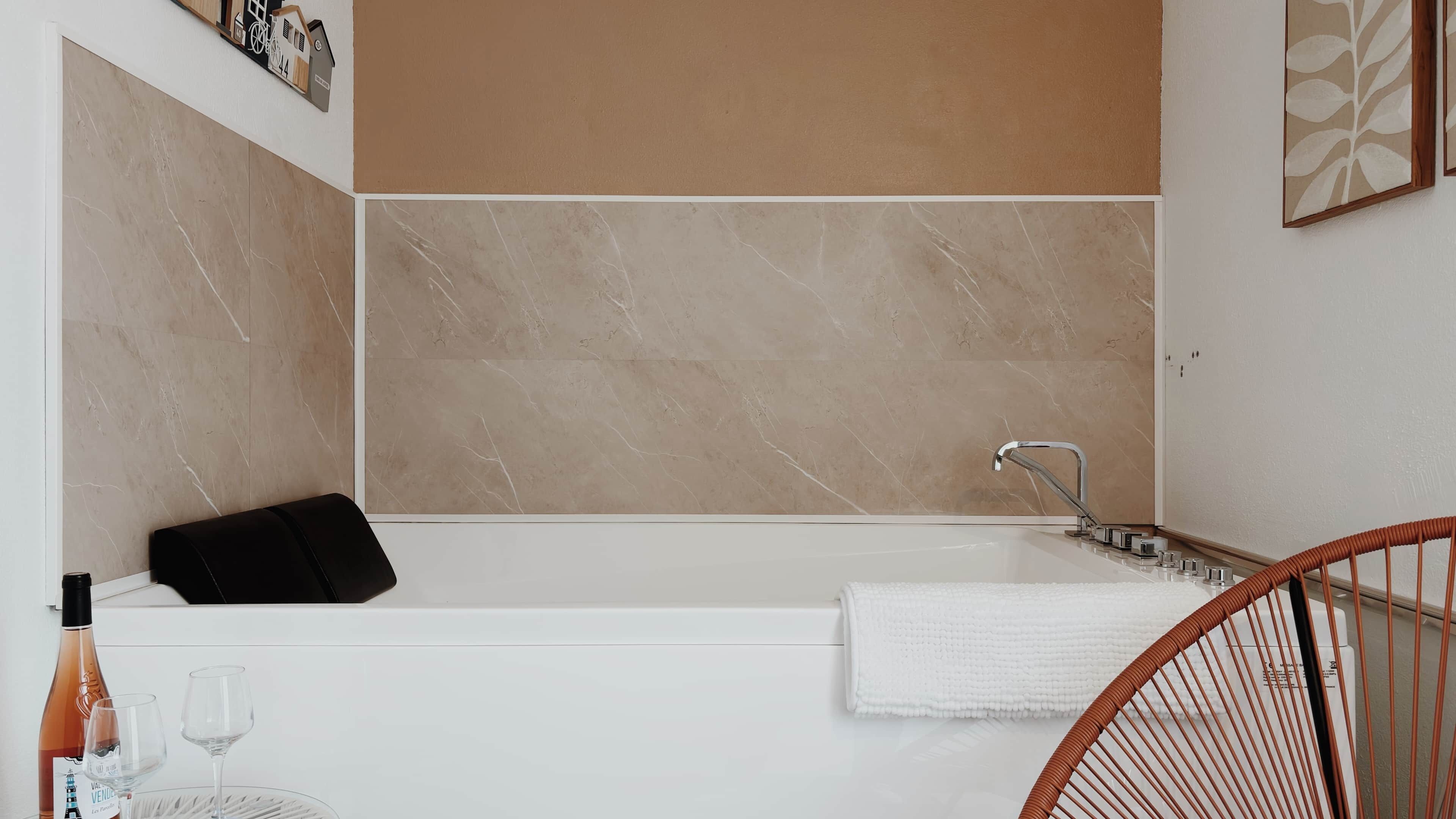 Une salle de bain moderne avec une baignoire, un lavabo blanc et une chaise en osier.