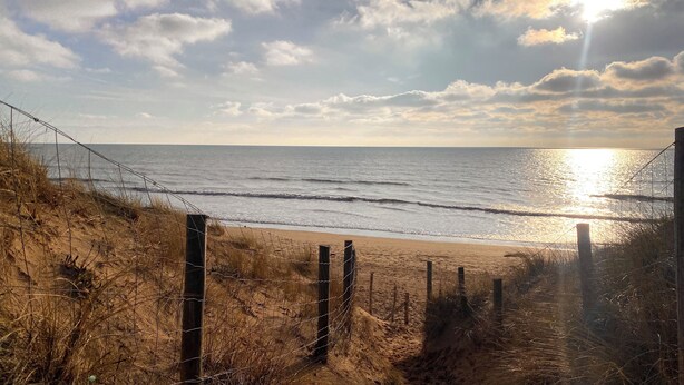 A beach with a sandy path leading to the water, bordered by a wire fence and wooden posts. - L'Atlantide Maison & Spa - Direct access to the beach (Saint-Hilaire-de-Riez)