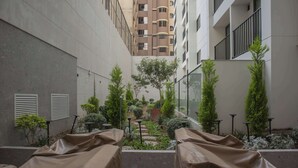 A covered outdoor seating area with tables, surrounded by greenery and a view of a multi-story building. - w* | Gorgeous 1BR w/ Terrace in Miraflores (Miraflores)