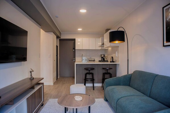Una sala de estar moderna con un sofá, una mesa de centro y un televisor montado en la pared.