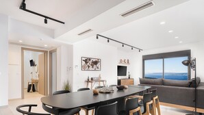 A modern dining area with a long table, black chairs, and a wooden floor. - Brand new 2025,  villa Cactus by NiMaR villas, stunning seaviews infinity pool (kokkino chorio)