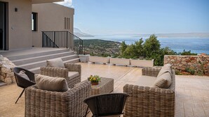 A terrace with wicker furniture and a view of the sea. - Brand new 2025,  villa Cactus by NiMaR villas, stunning seaviews infinity pool (kokkino chorio)