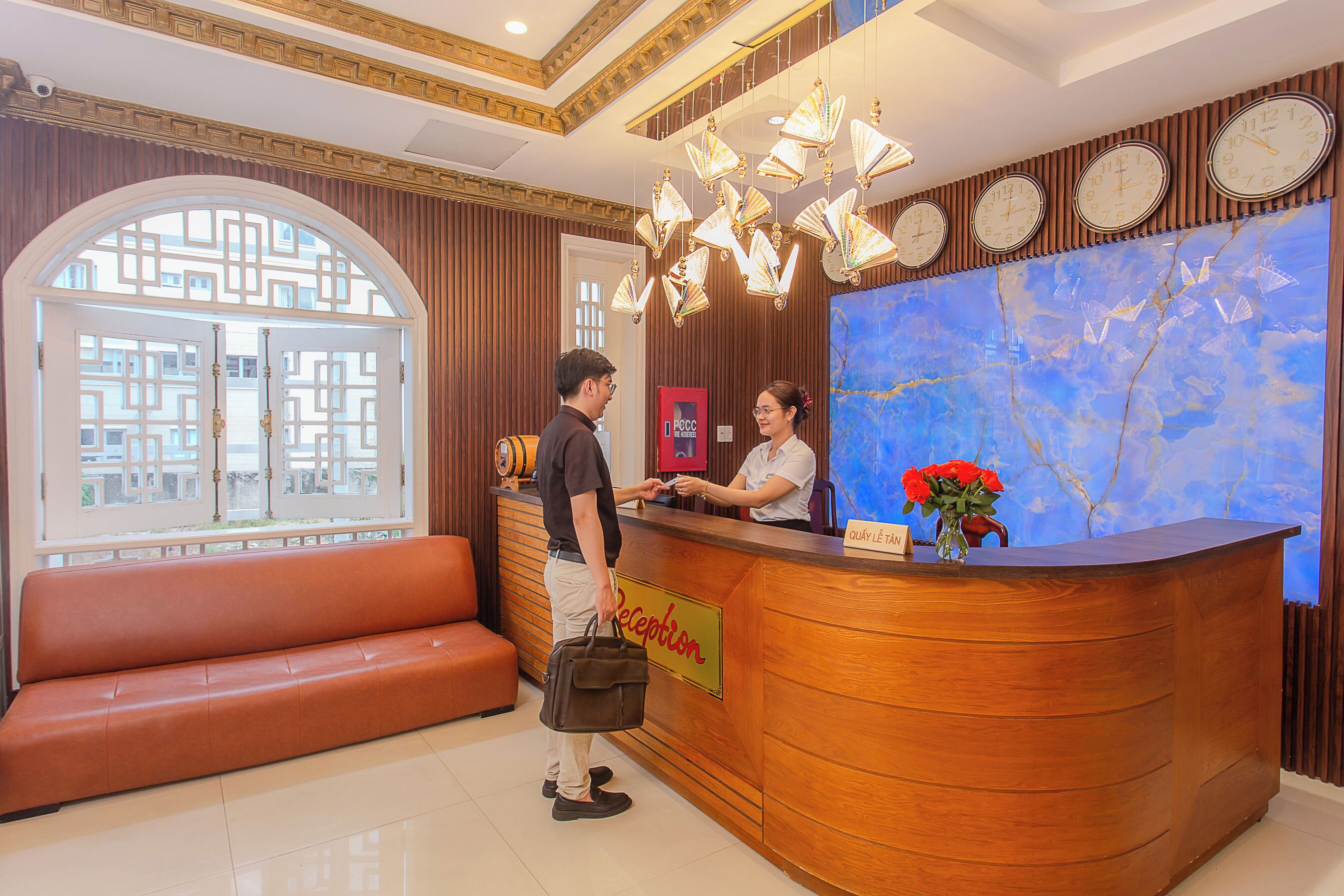 A reception area with a wooden reception desk, a bench, and a large window with a view of buildings.
