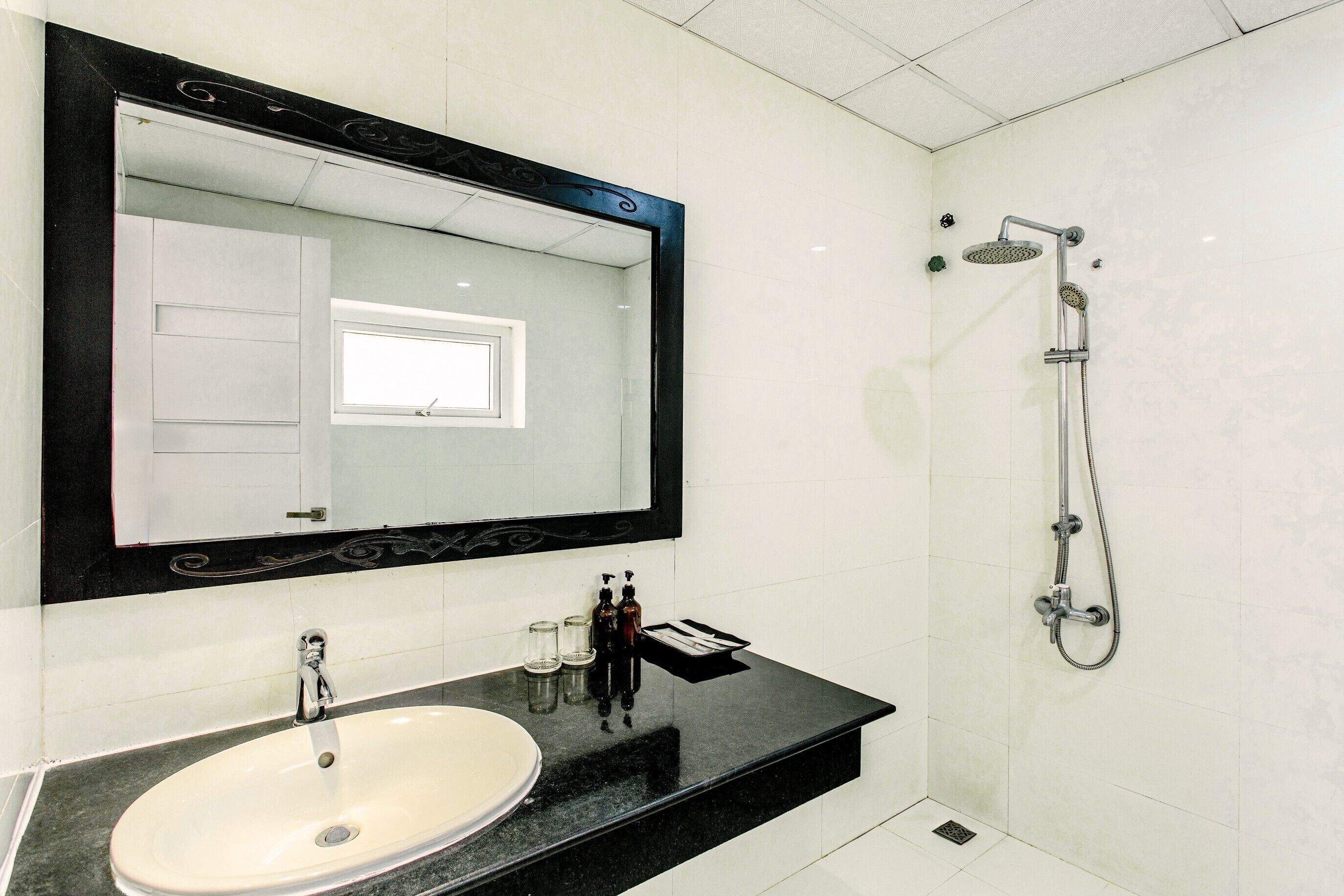 A bathroom with a large mirror, a sink, and a shower.