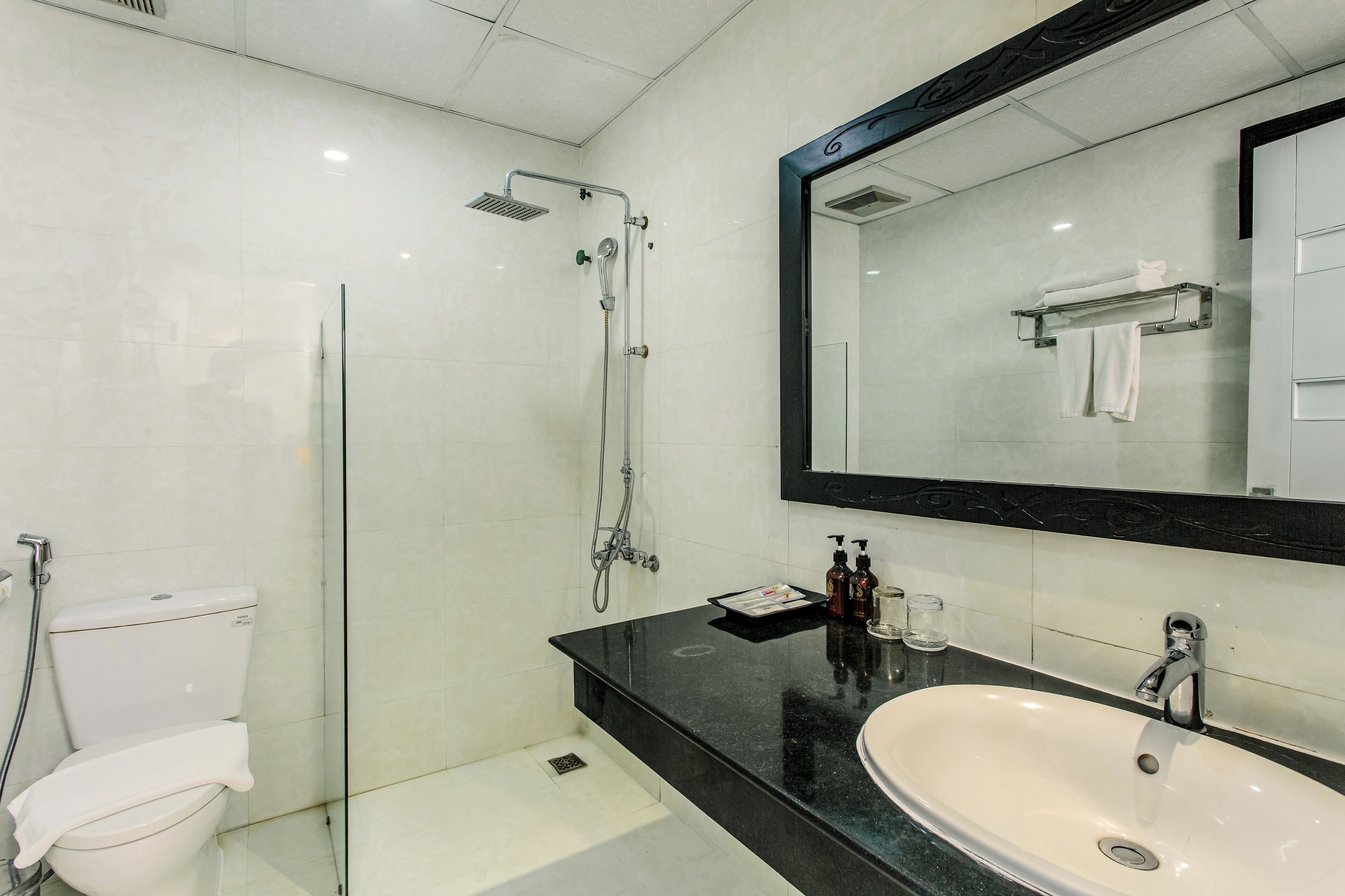 A modern bathroom with a glass-enclosed shower, a white sink, and a large mirror.