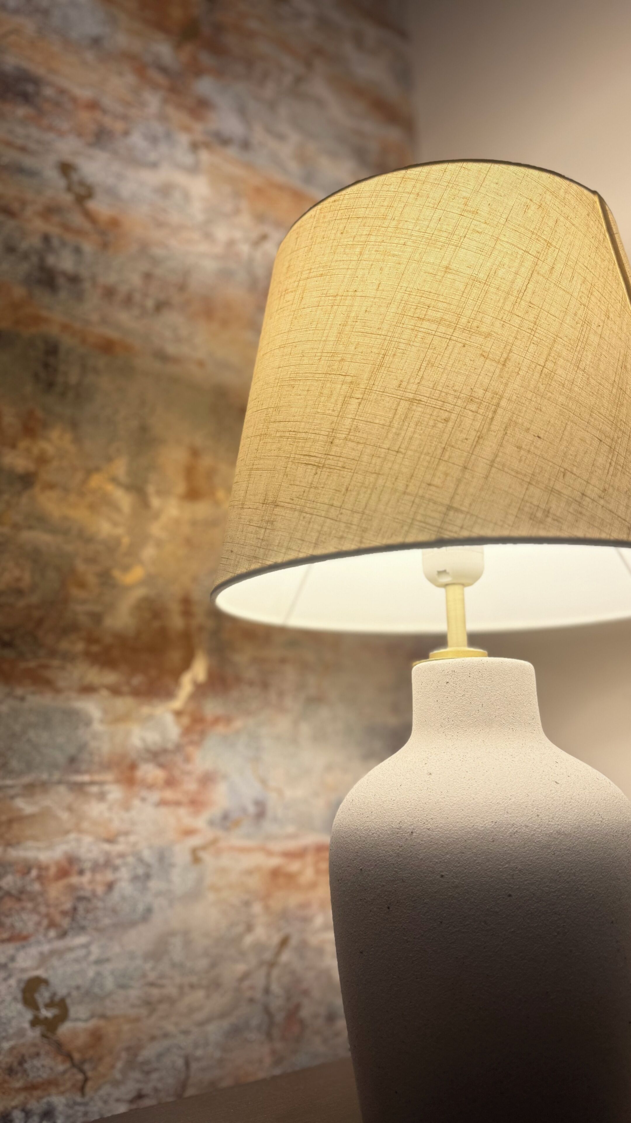 Une lampe avec un abat-jour texturé et un pied blanc.