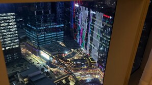 A nighttime cityscape with illuminated buildings and a busy street. - Luxury Uptown Parksuites - BGC (Taguig)