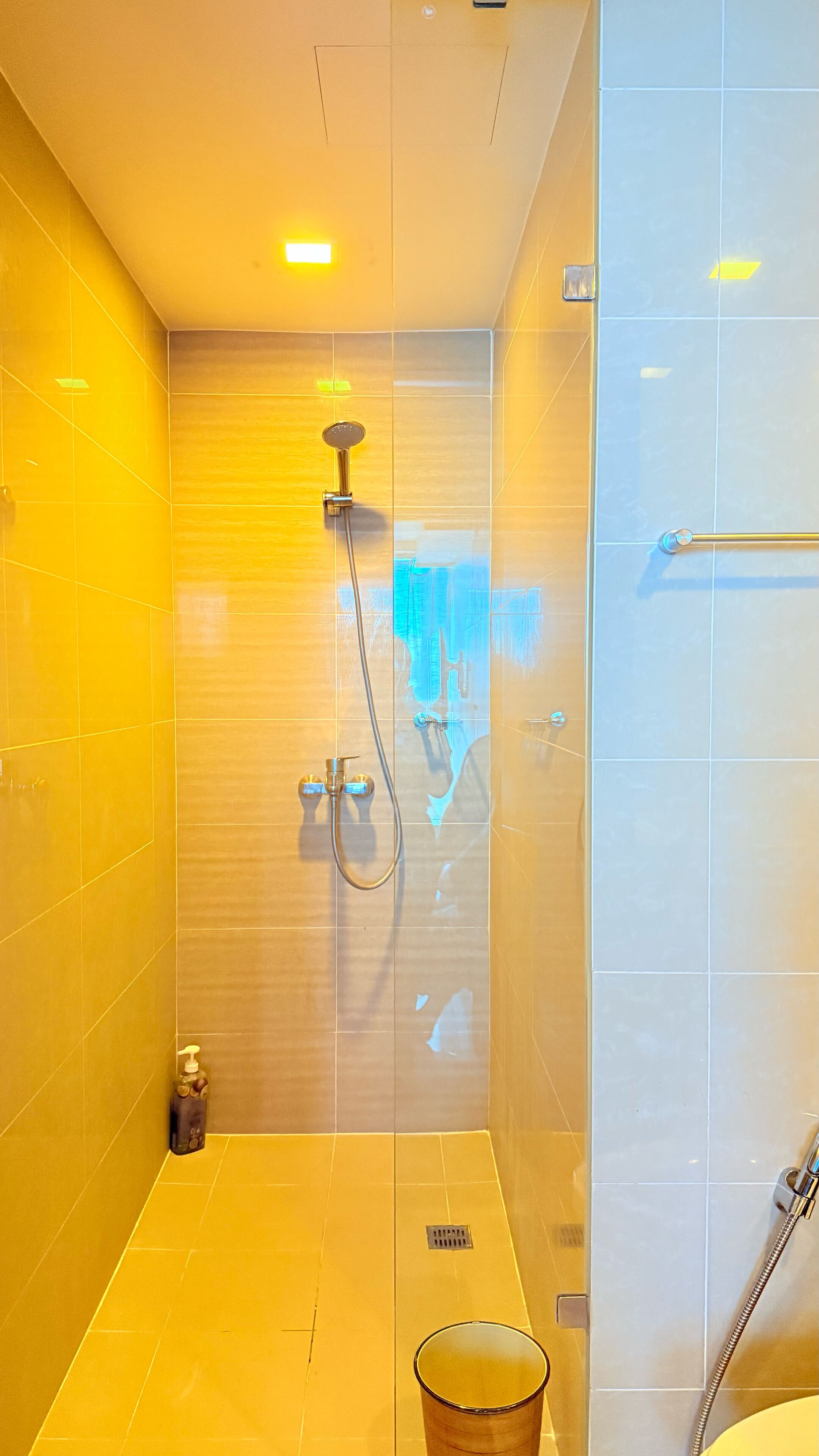 Un baño moderno con cabina de ducha de vidrio, cabezal de ducha manual y grifo monomando.