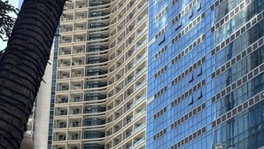 A multi-story building with a classical facade, including columns and arches, and a modern glass building adjacent to it. - Luxury Uptown Parksuites - BGC (Taguig)