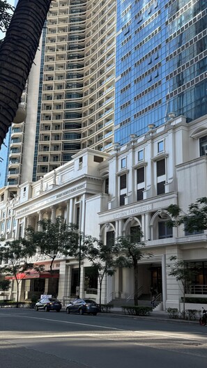 A multi-story building with a classical facade, including columns and arches, and a modern glass building adjacent to it. - Uptown Parksuites Tower One (Taguig)