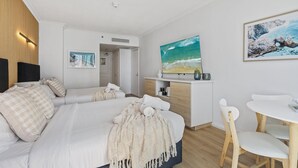 Ein modernes Hotelzimmer mit einem großen Bett, einem Schreibtisch mit Fernseher und einem Essbereich.