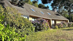 Ett hus med ett sluttande tak, takfönster och omgivet av grönska.